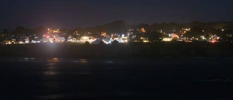 A nighttime view of a coastal town with illuminated buildings and a calm sea.