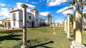 Un edificio blanco con una torre central y columnas en un césped cuidado.