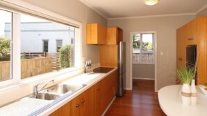 Eine moderne Küche mit Holzausstattung, einem Edelstahlkühlschrank und einem großen Fenster für natürliches Licht.