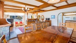 Ein geräumiger Essbereich mit einem Holztisch und -stühlen, einem Kamin und einer gemütlichen Sitzecke mit einer Couch und Sesseln.