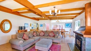 Ein gemütliches Wohnzimmer mit einer Eckcouch, Holzbalken, einem Kamin und einem Essbereich.