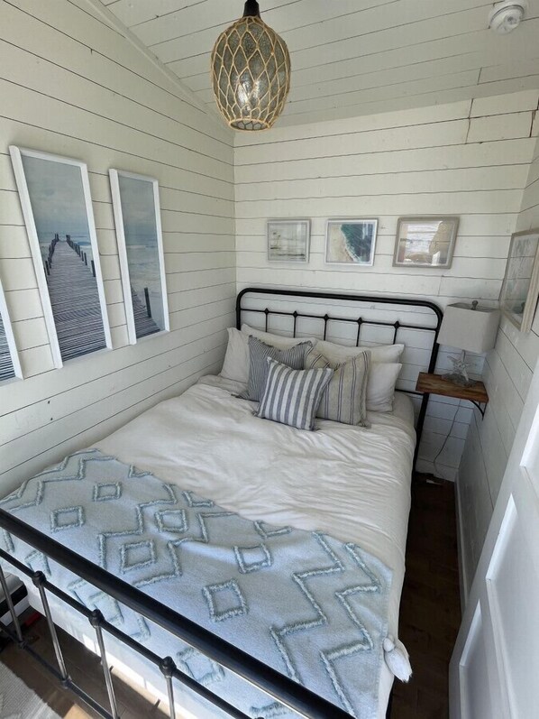 A bedroom with a bed, a nightstand, a lamp, and wall art.
