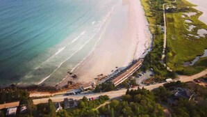 Vue aérienne d’une zone côtière comprenant une plage, une route et un petit village.