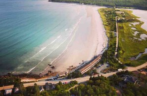 Vue aérienne d’une zone côtière comprenant une plage, une route et un petit village.