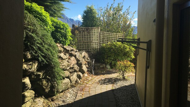 Un sendero de piedra que conduce a un edificio con vistas a montañas y una valla de madera.