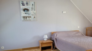 Et soveværelse med en træseng, et natbord med en lampe og et billedværk på væggen.