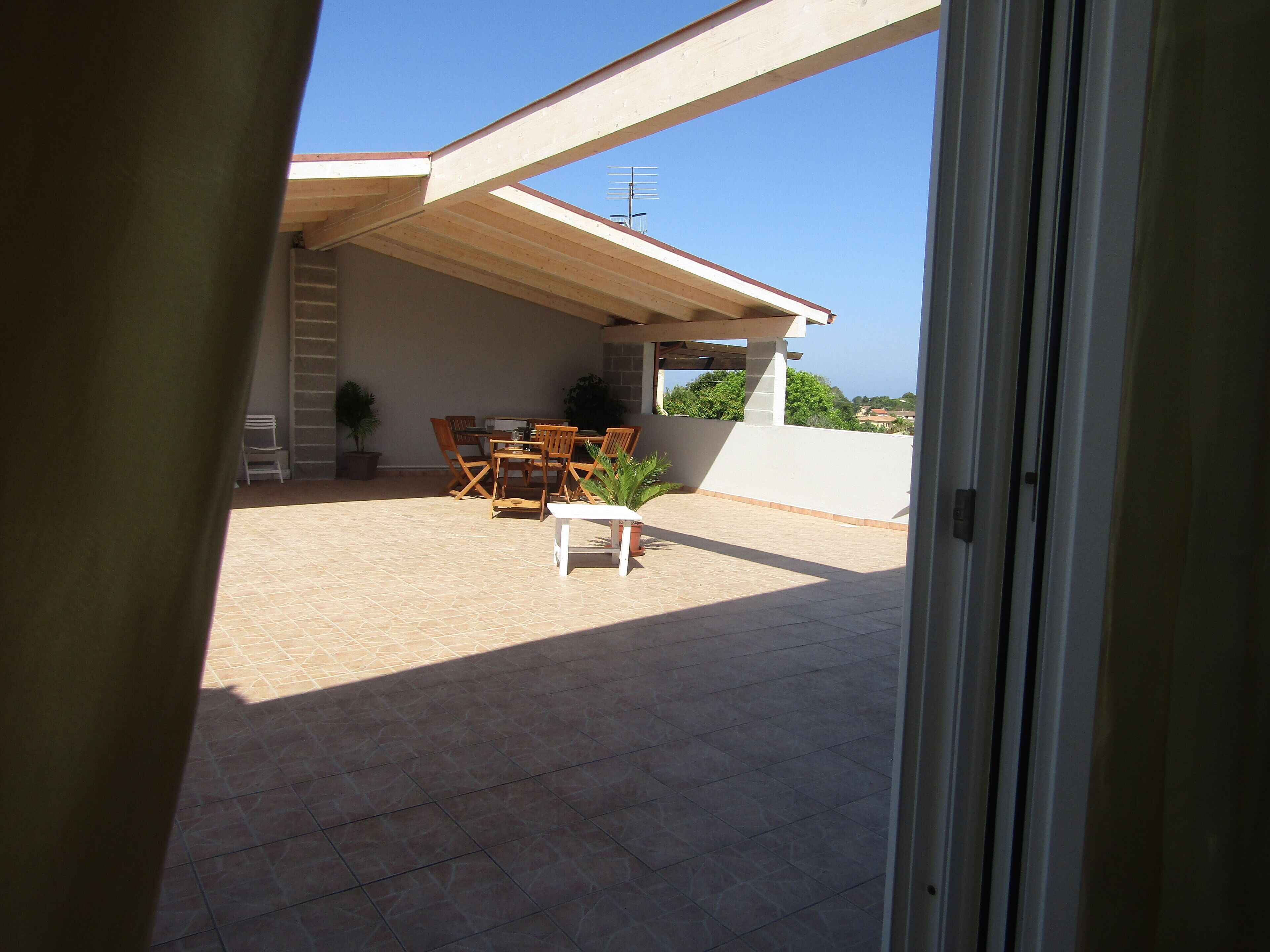 A patio with a table and chairs, a potted plant, and a view of the sky.