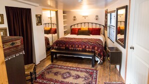 Une chambre à coucher comprenant un lit, un banc, une table de chevet, un miroir et un tapis à motifs.