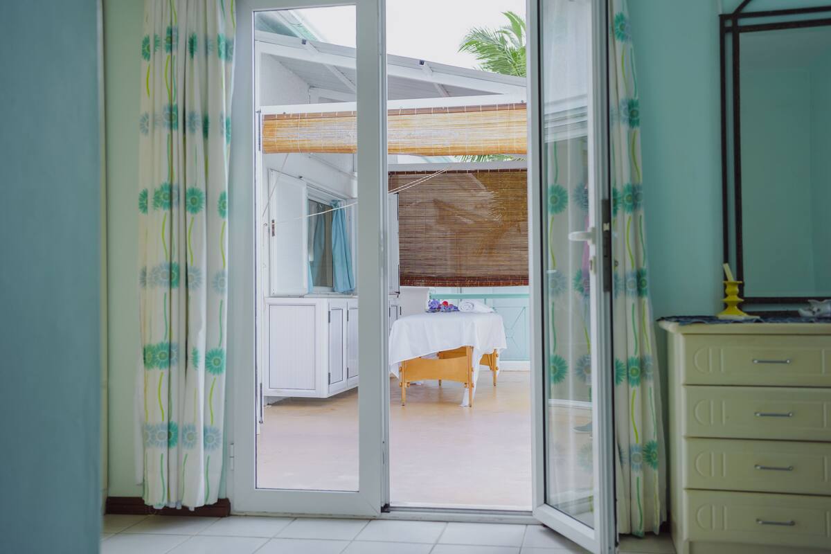 Quarto com porta de correr de vidro que dá para área externa com mesa e cadeiras.