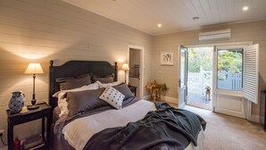 Une chambre à coucher avec un lit, des lampes de chevet, une table de chevet, une plante en pot et une vue sur l’extérieur.