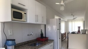 Een moderne keuken met witte kasten, een granieten aanrecht, een magnetron, een koelkast en een gasfornuis.