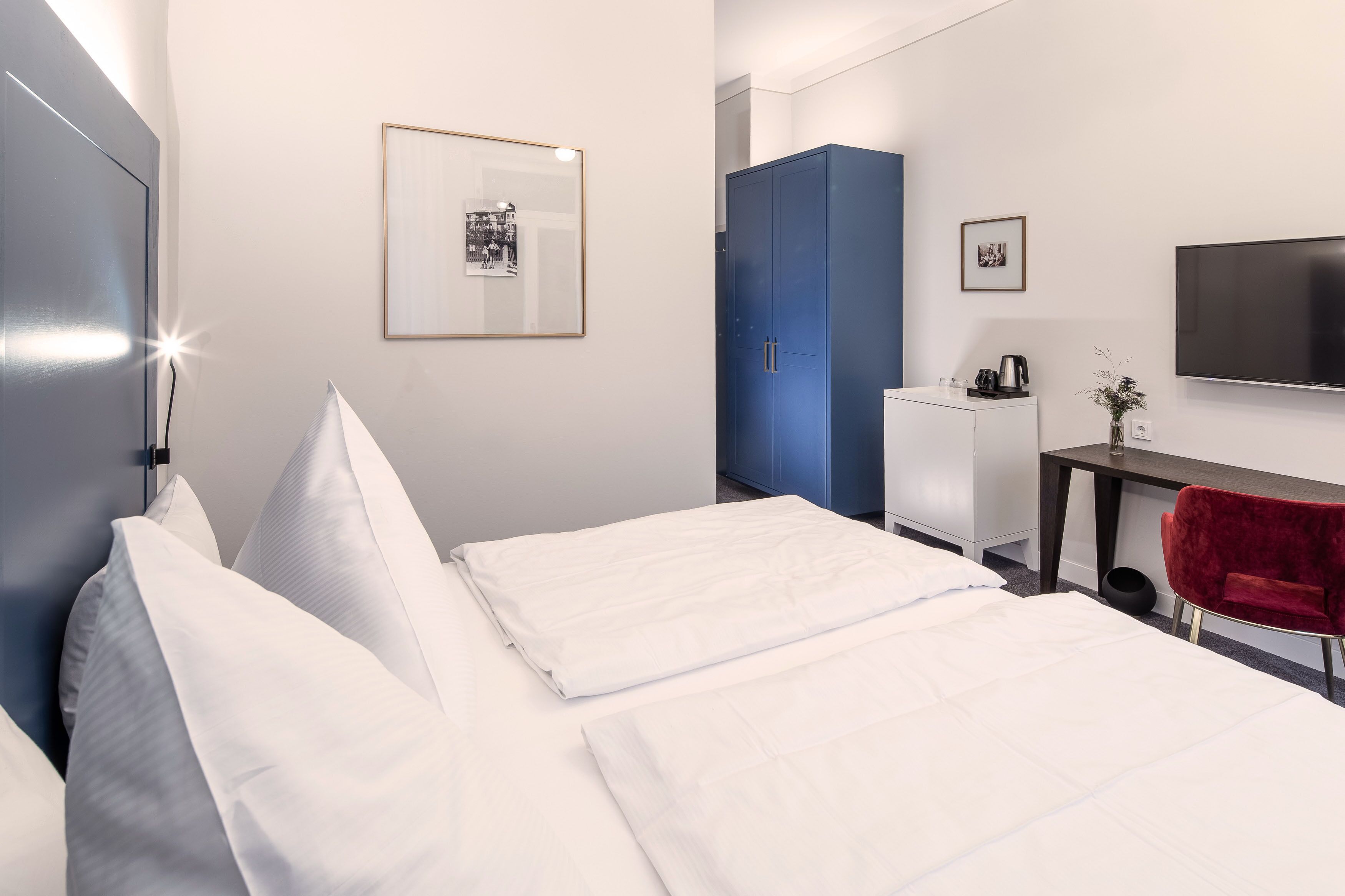 Une chambre d’hôtel avec un lit, un bureau, une télévision et une armoire.