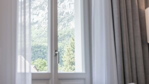 A room with a bed, a window with curtains, and a view of mountains. - Villa Rein Boutiquehotel (Bad Reichenhall)