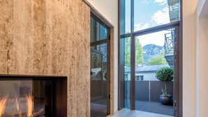 A modern interior with a fireplace, large glass doors leading to a balcony, and a view of the outdoors. - Villa Rein Boutiquehotel (Bad Reichenhall)