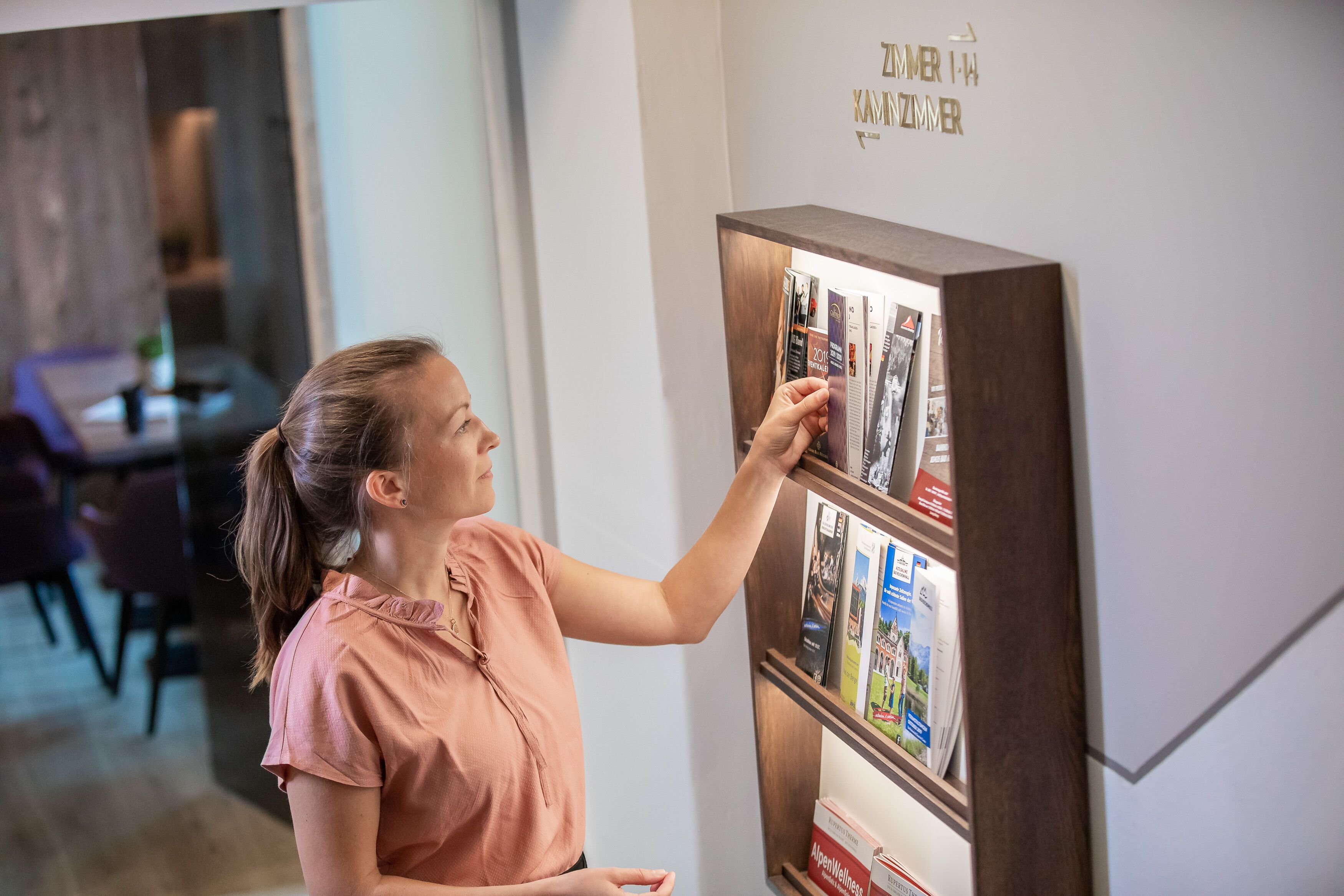 A person interacting with a display of magazines or brochures.