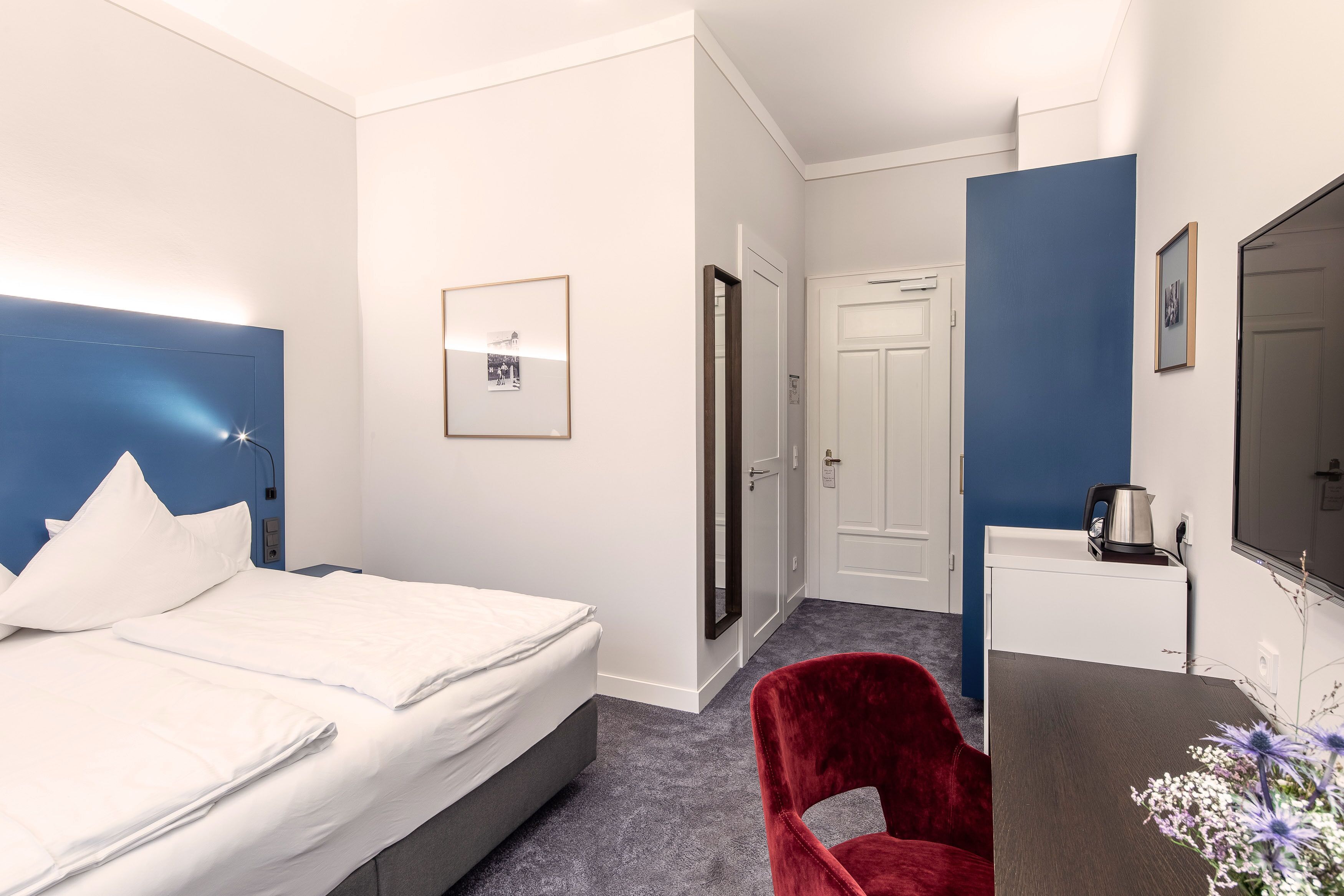 Ett hotellrum med en säng, ett skrivbord, en stol och en tv.