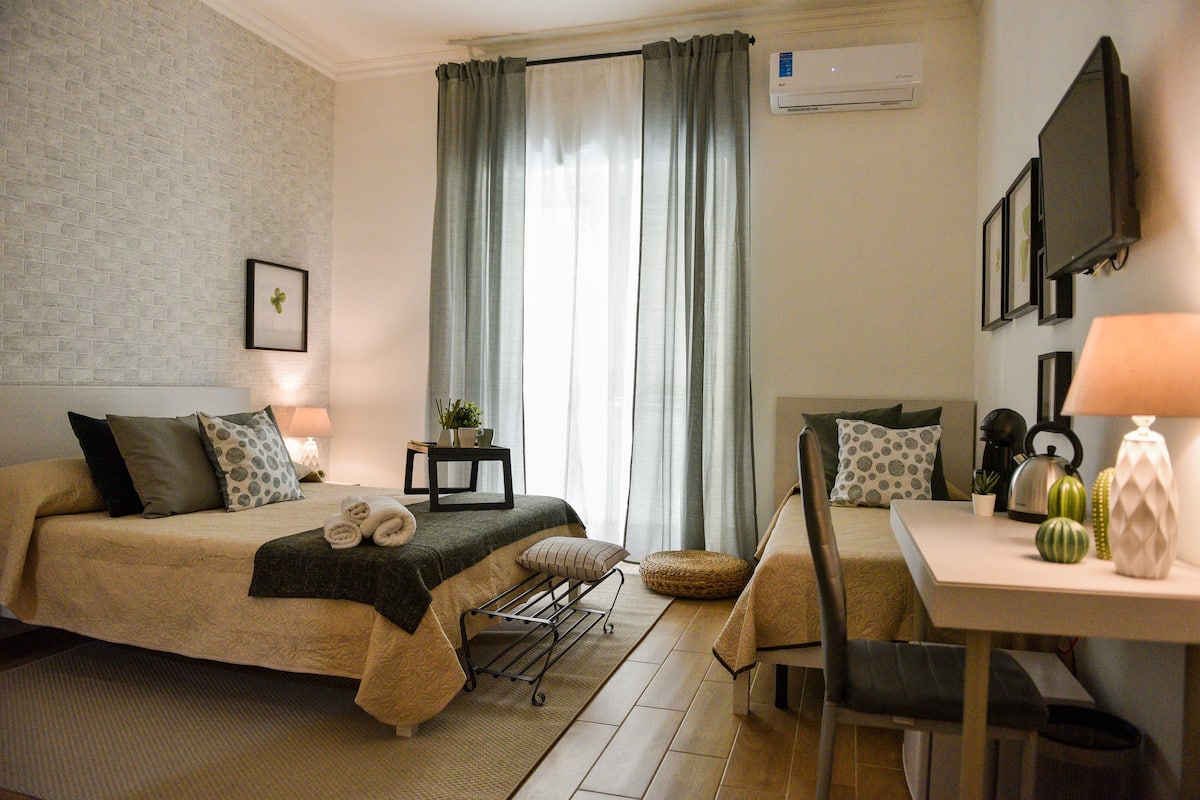 Ein ordentlich eingerichtetes Schlafzimmer mit Bett, Nachttisch, Lampe und einem kleinen Tisch mit Pflanze.