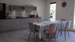 Et moderne køkken med grå skabe, en indbygget mikrobølgeovn og et spiseområde med et bord dækket til fire personer.