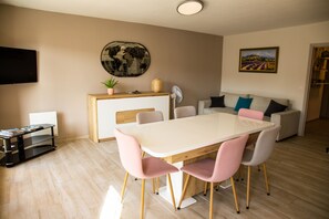 Ein modernes Wohnzimmer mit Essbereich, einer Couch, einem Fernseher und einem Bild an der Wand.