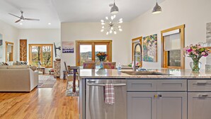 A spacious kitchen with a central island, wooden flooring, and modern appliances. - Upstream Bachelorette Oasis - DOWNTOWN LOCATION! (Asheville)
