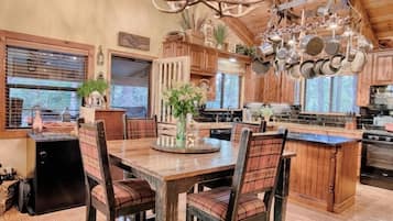 A rustic kitchen with wooden cabinets, a large island, and a unique antler chandelier.