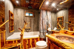 A rustic bathroom with a wooden bathtub, a toilet, and a sink with a decorative basin. - Cutest Cabin in Pinetop with jacuzzi tub! Walk to Jackson Lake in minutes! (Pinetop)
