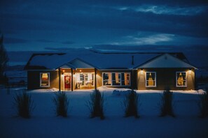 A two-story house with a front porch and a covered entryway, surrounded by snow. - Bear Lake Gathering House- PRIVATE pool! Sleeps 30+, pets with approval! (Montpelier)