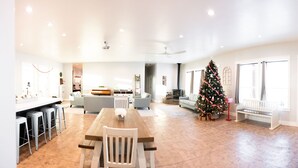 Een ruime woonkamer met een eettafel, banken en een kerstboom.