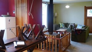 Un salon chaleureux avec une table en bois, un canapé vert et un réfrigérateur blanc.