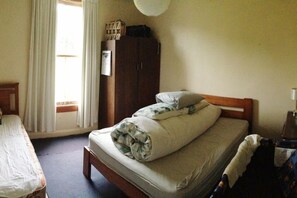 Een slaapkamer met een bed, een kledingkast en een raam met gordijnen.