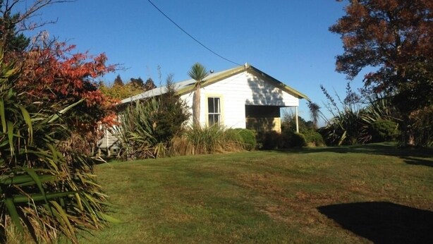 Une maison de plain-pied avec un toit à pignon, un garage à l’avant et une pelouse bien entretenue.
