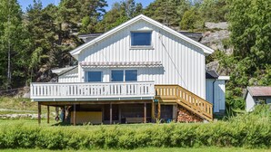 A two-story house with a balcony, a garage, and a small shed in a wooded area. - Nice home in Vesterøy with WiFi (Vesterøy)