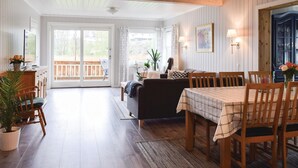A spacious living area with a sofa, dining table, and chairs. There is a sliding glass door leading to an outdoor deck. - Nice home in Vesterøy with WiFi (Vesterøy)