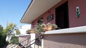 A building with a pink facade, a staircase, and potted plants. - Villetta Orchidea (Giuggianello)