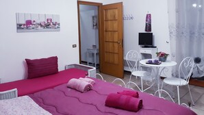 A room with two beds, a desk, a chair, a television, and a small table with a vase. - Villetta Orchidea (Giuggianello)