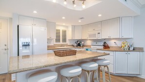 A modern kitchen with white cabinetry, a granite countertop, and a built-in island with bar stools.
