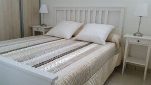 A neatly made bed with a striped bedspread, two pillows, and a headboard. There are two bedside tables with lamps on either side of the bed. - T2 comfortable with aircon (La Londe-Les-Maures)