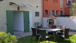A patio with a table and chairs, an outdoor grill, and a green door. - T2 comfortable with aircon (La Londe-Les-Maures)