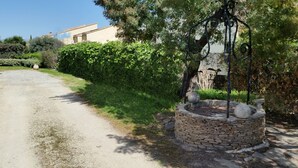 A gravel path leading to a stone fountain surrounded by lush greenery and a building in the background. - T2 comfortable with aircon (La Londe-Les-Maures)