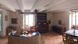 A room with a dining area, a wicker chair, a wooden table, and a cabinet with dishes. - Maison de Pêcheur, Port de Penerf. One of a kind! (Damgan)