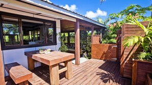 A wooden deck with a table and benches, surrounded by plants and a wooden fence. - Nevaeh Holiday Home + Pool + Unlimited Internet (Tupapa)