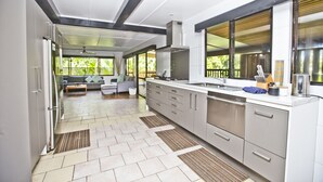 A modern kitchen with a central island, stainless steel appliances, and large windows. - Nevaeh Holiday Home + Pool + Unlimited Internet (Tupapa)