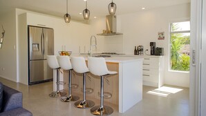 A modern kitchen with a central island, stainless steel appliances, and pendant lighting.