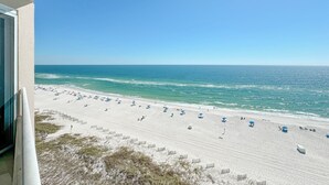 Une plage bordée de rangées de parasols et de chaises longues, un ciel dégagé et l’océan.