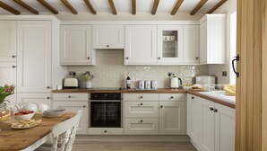 Een moderne keuken met witte kasten, houten balken en een houten aanrecht.