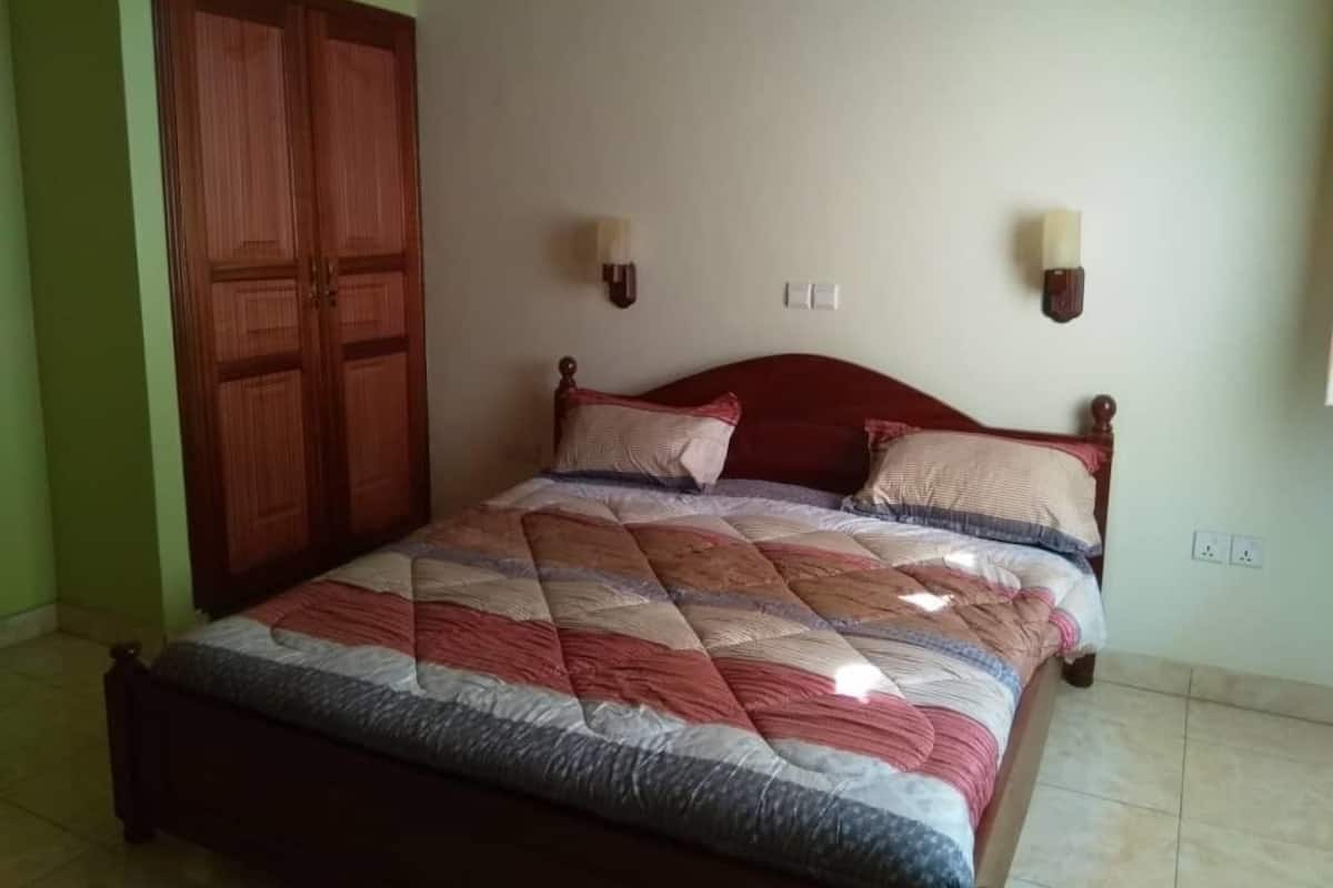 A bedroom with a wooden bed, two wall-mounted lamps, and a wardrobe.
