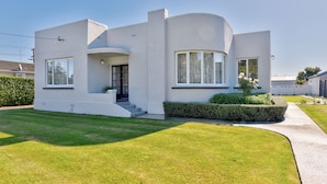 A modern two-story house with a curved facade, a front porch, and a well-maintained lawn.