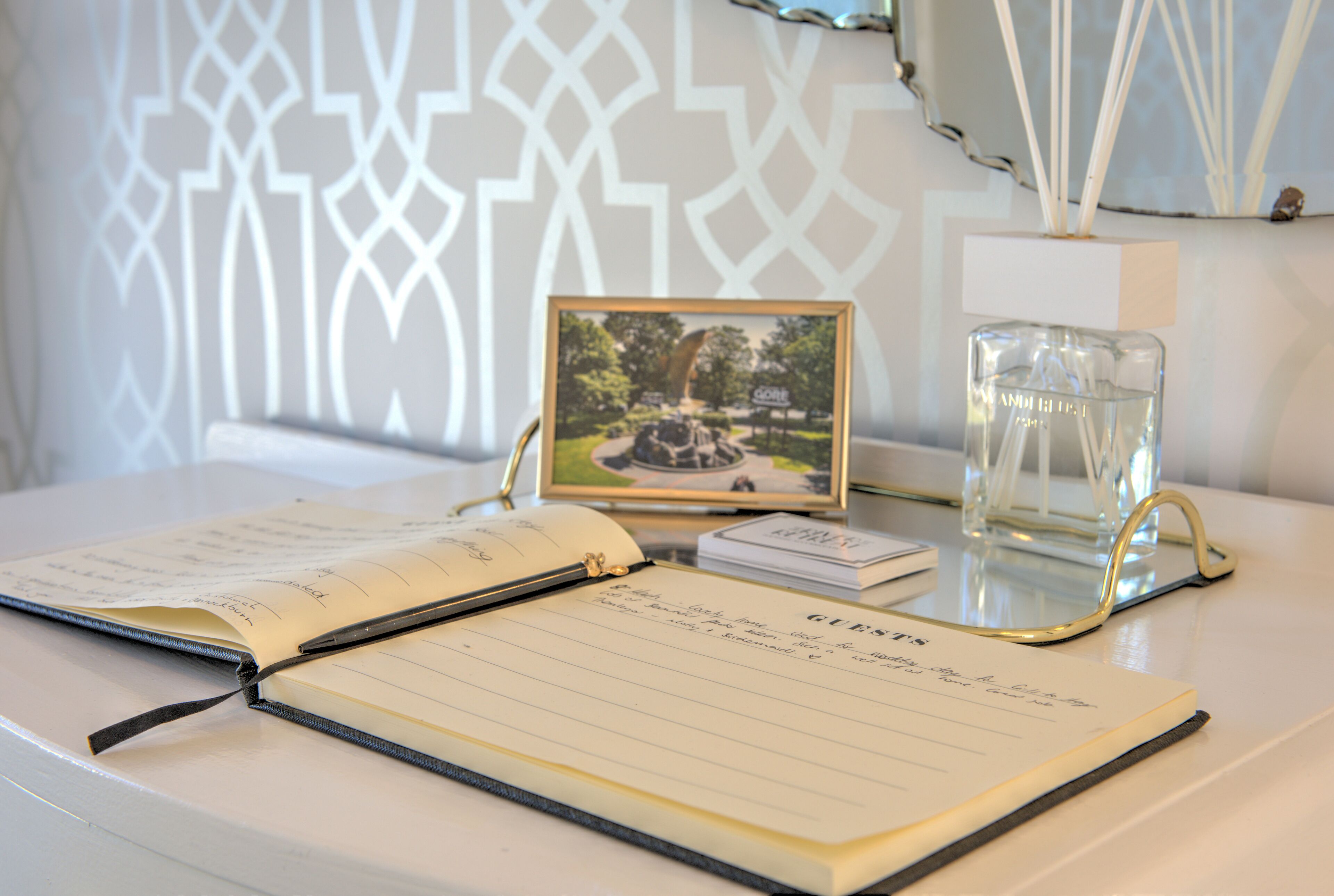 An open notebook with lined pages, a framed photograph, and a clear glass container on a table.