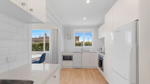 A modern kitchen with white cabinetry, a dishwasher, an oven, and a refrigerator.