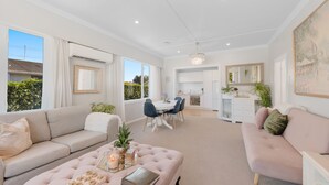 A spacious living area with a sofa, ottoman, and dining table.
